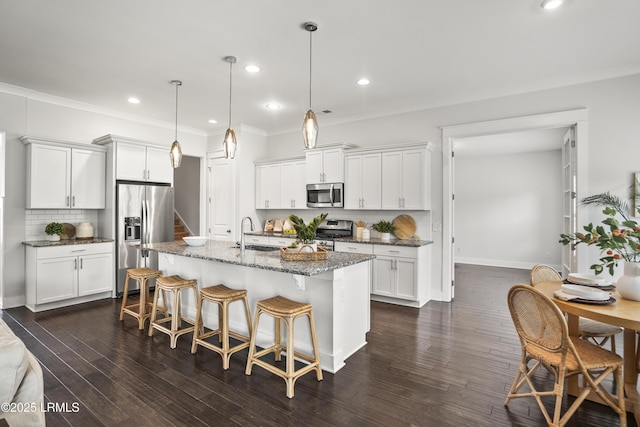 135 Danbridge Ct, Bluffton, SC 29910 - kitchen with appliances with stainless steel finishes, backsplash, an island with sink, dark stone counters, and a kitchen breakfast bar