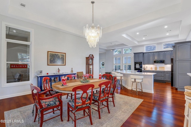 dining room featuring an inviting chandelier, dark wood-type flooring, and a raised ceiling