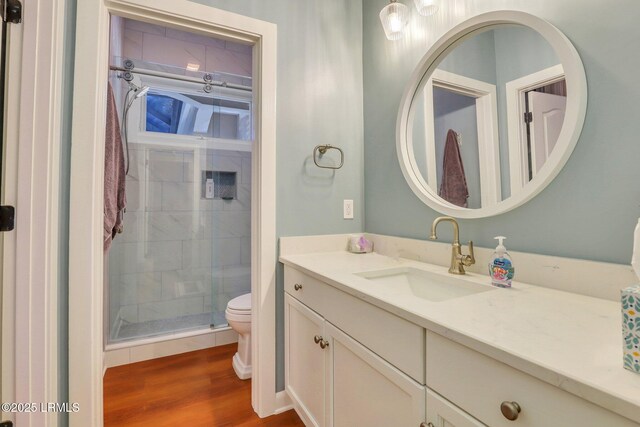 bathroom featuring wood-type flooring, toilet, an enclosed shower, and vanity