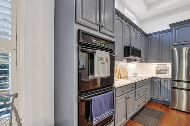 kitchen with gray cabinets, tasteful backsplash, dark hardwood / wood-style flooring, and black appliances