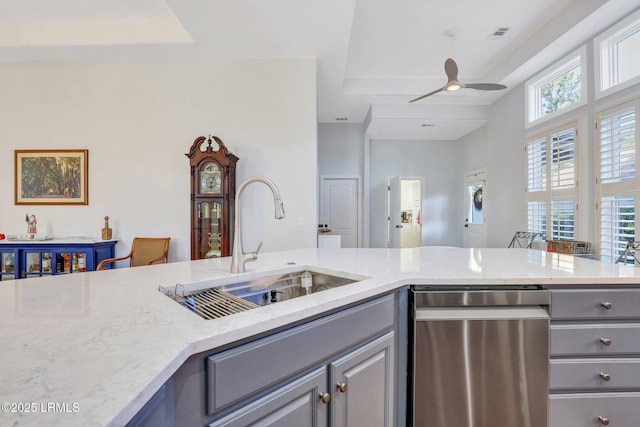 kitchen with sink, gray cabinets, ceiling fan, light stone counters, and stainless steel dishwasher