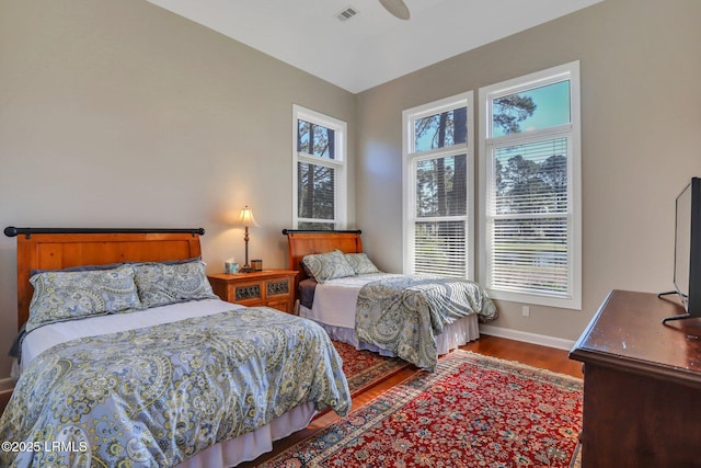 bedroom featuring ceiling fan, wood-type flooring, and multiple windows