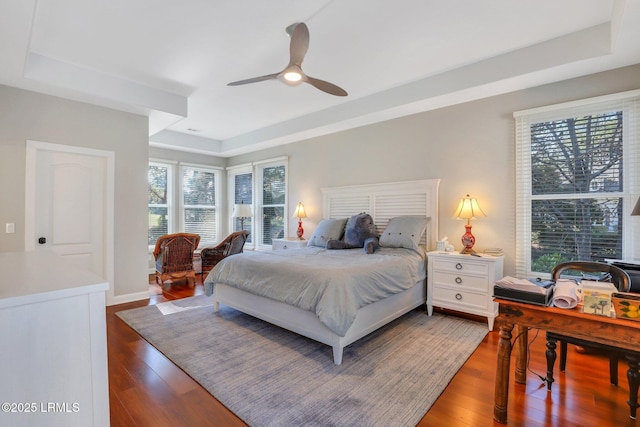 bedroom with ceiling fan, dark hardwood / wood-style flooring, and a raised ceiling