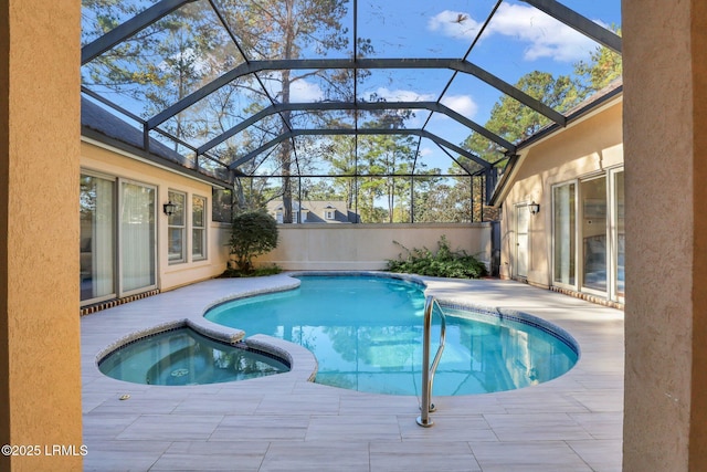 view of pool with an in ground hot tub, glass enclosure, and a patio area