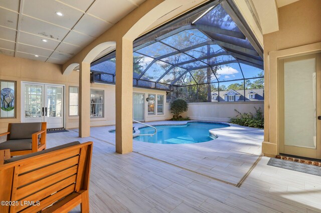 view of swimming pool with french doors, glass enclosure, and a patio area