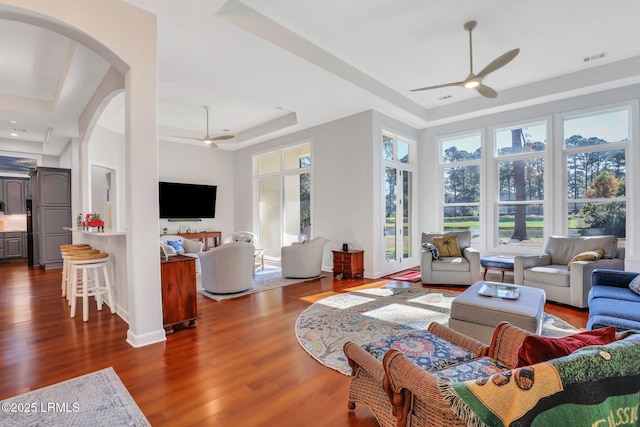 living room featuring a raised ceiling, dark hardwood / wood-style floors, and ceiling fan