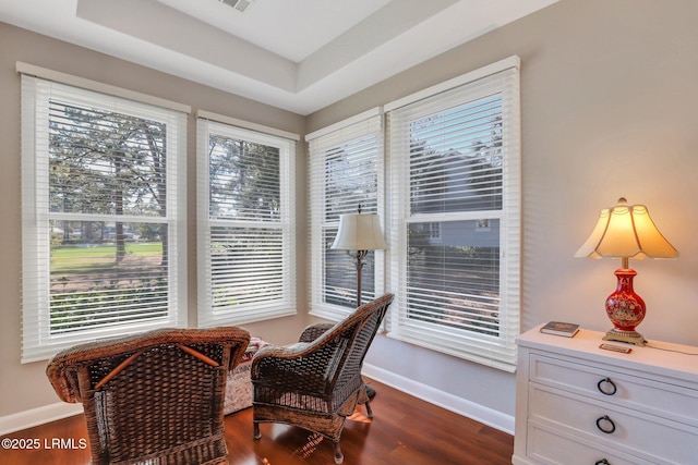 sitting room featuring dark wood-type flooring and a tray ceiling