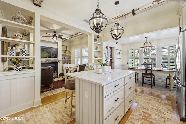 625 Spanish Wells Rd Unit 12, Hilton Head Island, SC 29926 - kitchen featuring freestanding refrigerator, light stone countertops, a fireplace, ceiling fan with notable chandelier, and decorative light fixtures