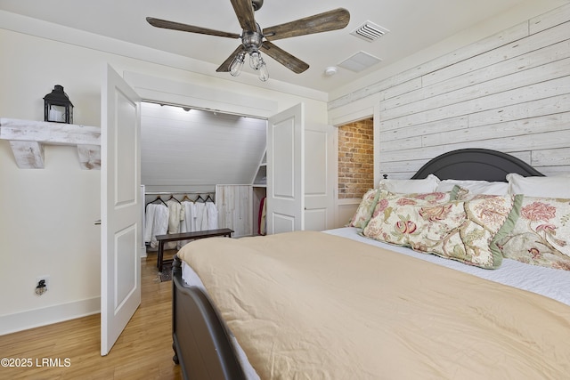 625 Spanish Wells Rd Unit 12, Hilton Head Island, SC 29926 - bedroom with visible vents, baseboards, ceiling fan, wooden walls, and light wood-style flooring