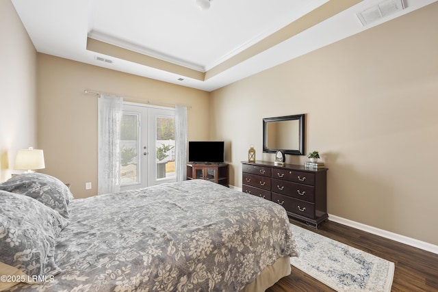 bedroom featuring dark hardwood / wood-style floors, ornamental molding, access to exterior, a raised ceiling, and french doors