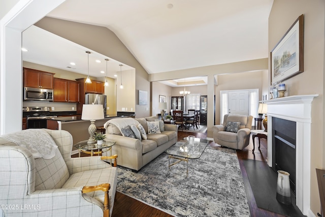 living room with an inviting chandelier, vaulted ceiling, and light wood-type flooring