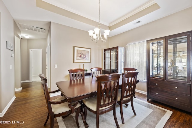 dining space with a chandelier, dark hardwood / wood-style flooring, a raised ceiling, and crown molding