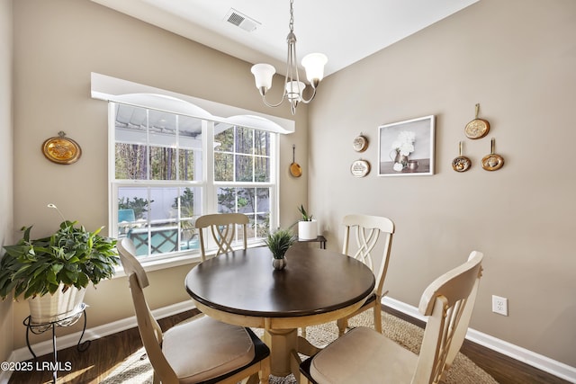 dining room with dark wood-type flooring, a wealth of natural light, and an inviting chandelier