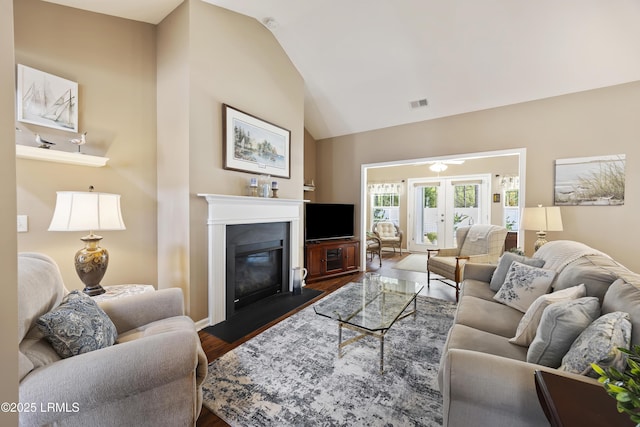 living room featuring lofted ceiling, dark wood-type flooring, and french doors