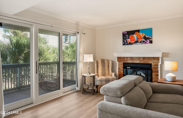 living room featuring crown molding, light hardwood / wood-style flooring, and a tile fireplace