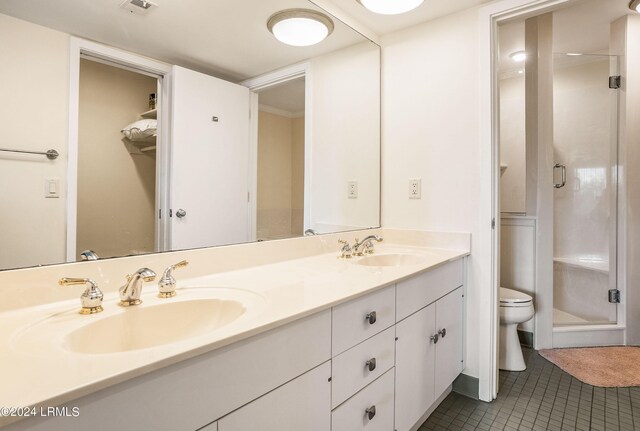 bathroom with vanity, a shower with shower door, tile patterned floors, and toilet