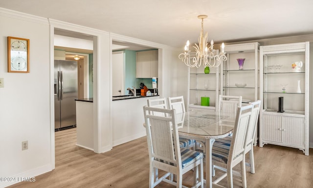 dining area with crown molding, sink, light hardwood / wood-style flooring, and a notable chandelier