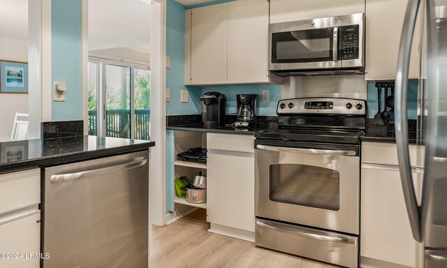 kitchen with white cabinetry, appliances with stainless steel finishes, and dark stone counters