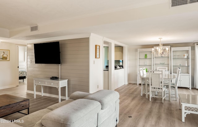 living room with crown molding, light hardwood / wood-style flooring, and a notable chandelier