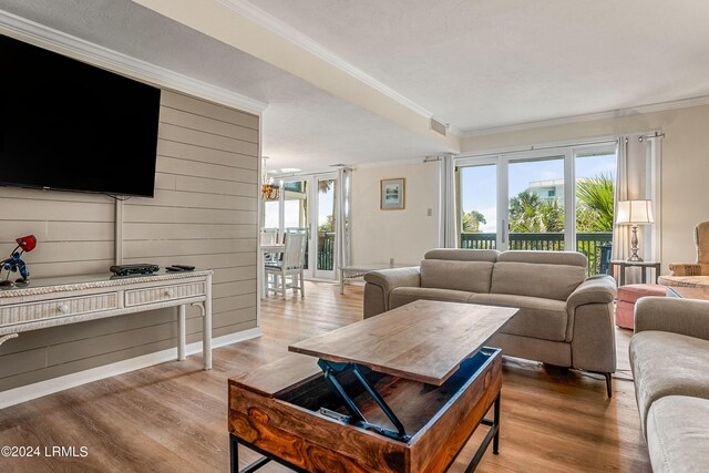 living room featuring ornamental molding, wood walls, and light wood-type flooring