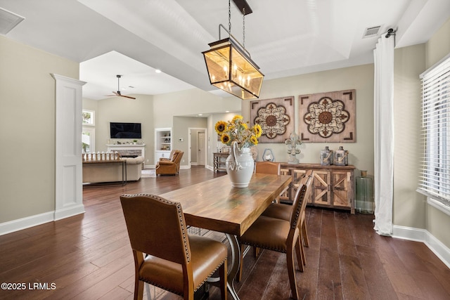8 Wild Magnolia Ln, Okatie, SC 29909 - dining space featuring baseboards, a fireplace, dark wood-type flooring, visible vents, and ceiling fan with notable chandelier
