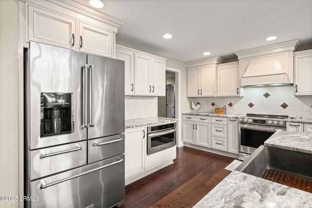 8 Wild Magnolia Ln, Okatie, SC 29909 - kitchen featuring light stone countertops, dark wood-type flooring, premium range hood, and appliances with stainless steel finishes