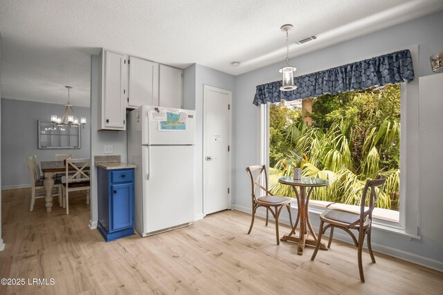 26 Fairway Club Dr, Fripp Island, SC 29920 - kitchen with blue cabinetry, baseboards, freestanding refrigerator, a chandelier, and light wood-style flooring