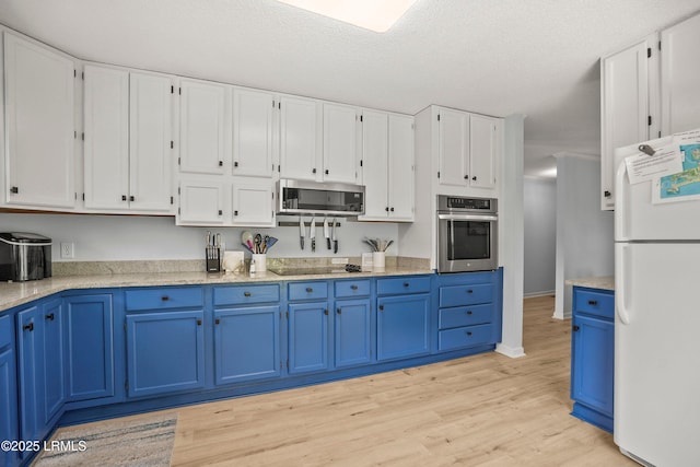 26 Fairway Club Dr, Fripp Island, SC 29920 - kitchen featuring white cabinets, blue cabinetry, stainless steel appliances, baseboards, and light wood-type flooring