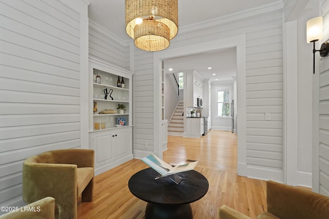 12 Sheffield Ct, Beaufort, SC 29907 - sitting room featuring stairway, light wood-style floors, a chandelier, ornamental molding, and wooden walls