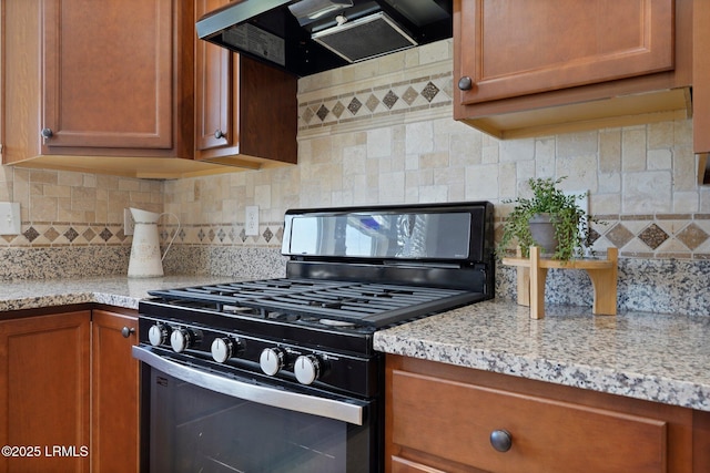 95 Sunrise Point Dr, Okatie, SC 29909 - kitchen with gas range, exhaust hood, brown cabinetry, decorative backsplash, and light stone countertops