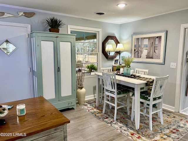 dining space featuring crown molding and light wood-type flooring