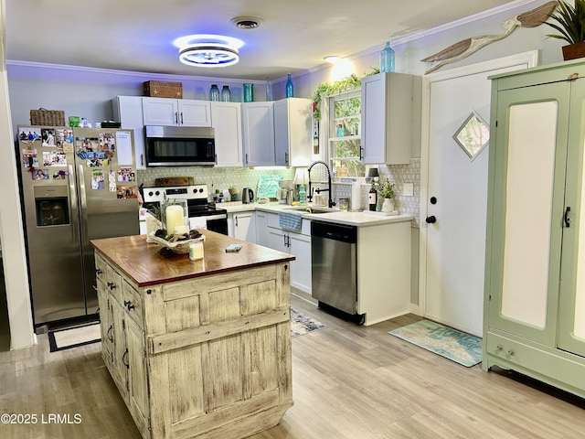 kitchen with a kitchen island, white cabinetry, backsplash, stainless steel appliances, and light wood-type flooring