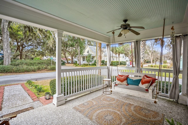 sunroom featuring plenty of natural light, a residential view, and a ceiling fan