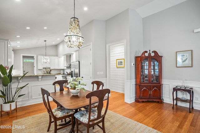 dining room with recessed lighting, a wainscoted wall, vaulted ceiling, and light wood finished floors