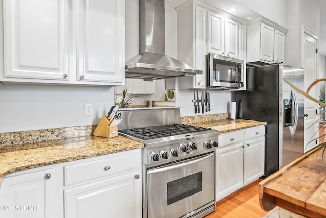 kitchen featuring wall chimney exhaust hood, white cabinetry, stainless steel appliances, and light wood-style flooring