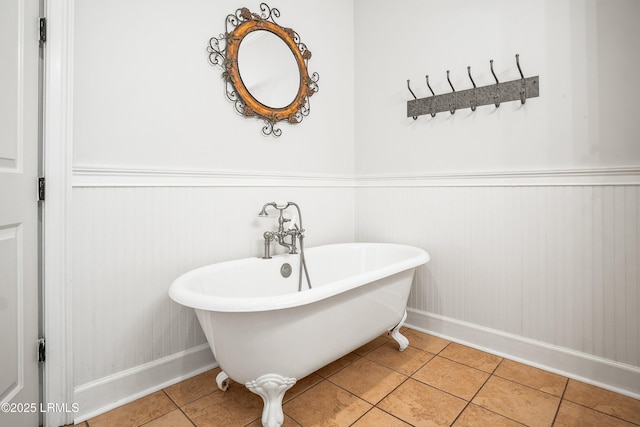 full bath with a freestanding bath, a wainscoted wall, and tile patterned flooring