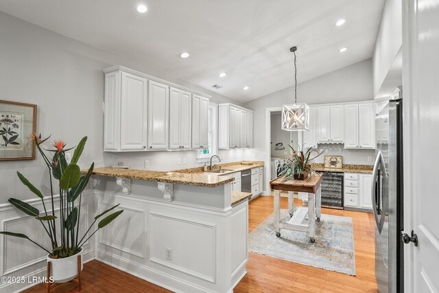 kitchen with beverage cooler, white cabinets, light wood-style flooring, appliances with stainless steel finishes, and a peninsula