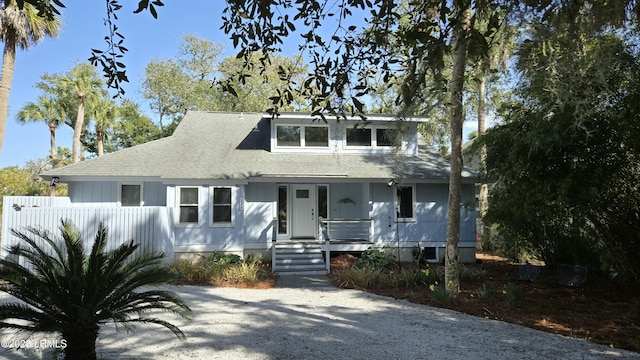 view of front of house featuring a porch, a shingled roof, and fence