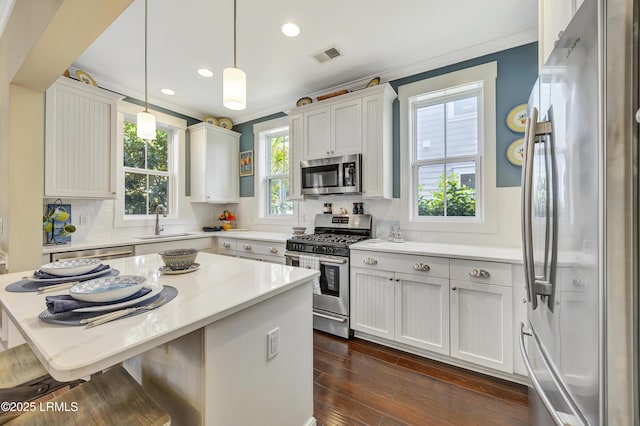 kitchen featuring sink, appliances with stainless steel finishes, white cabinetry, light stone counters, and decorative light fixtures