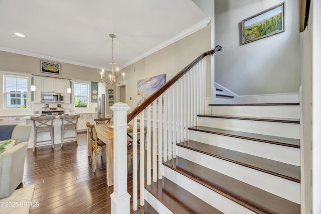 stairs featuring hardwood / wood-style flooring, ornamental molding, and a notable chandelier