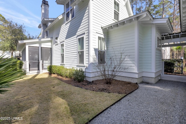 view of side of property with a sunroom and a lawn