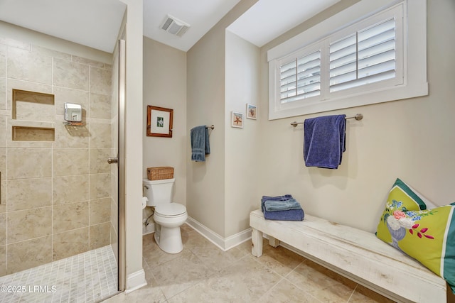 bathroom featuring a tile shower, tile patterned flooring, and toilet