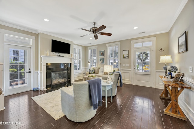 living room featuring dark wood-type flooring, ornamental molding, and ceiling fan