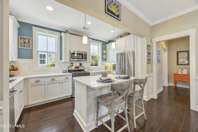 kitchen featuring pendant lighting, stainless steel appliances, a center island, and white cabinets