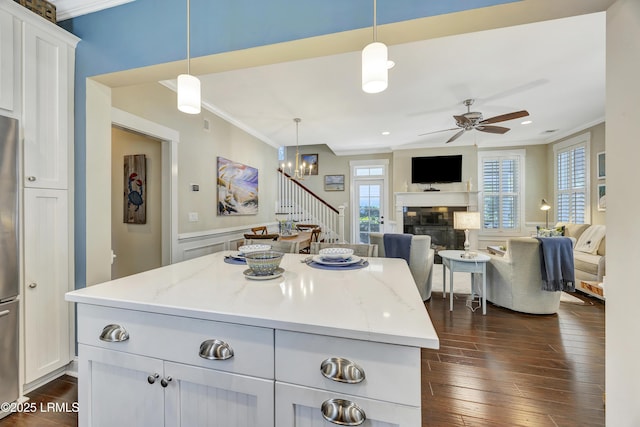 kitchen featuring crown molding, light stone counters, a center island, pendant lighting, and white cabinets