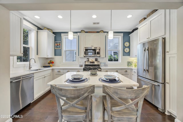 kitchen featuring sink, appliances with stainless steel finishes, a kitchen breakfast bar, a center island, and decorative light fixtures