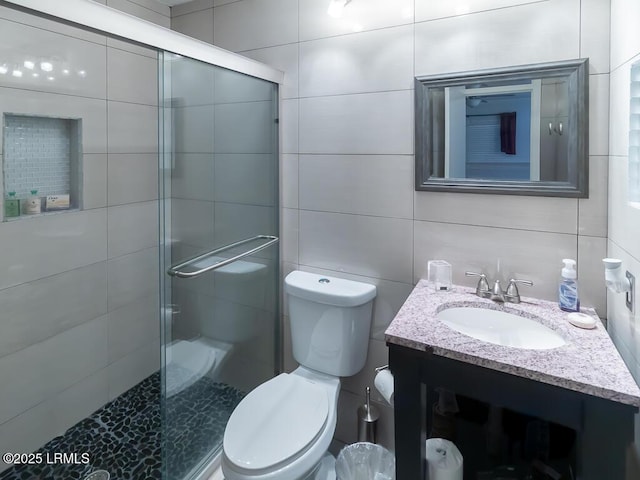 bathroom with vanity, tile walls, walk in shower, and toilet