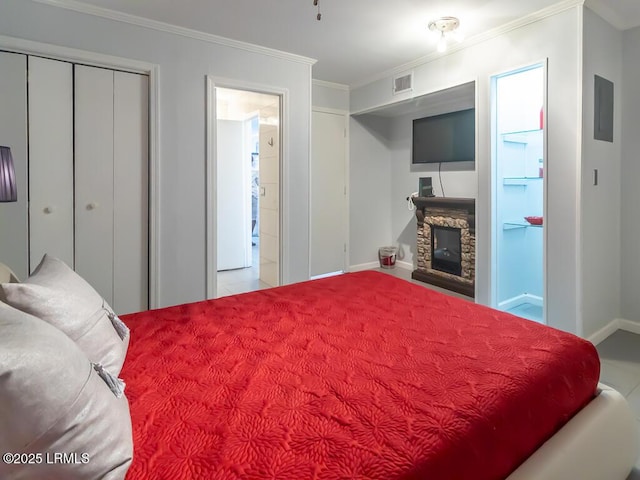 bedroom featuring crown molding, a stone fireplace, and a closet