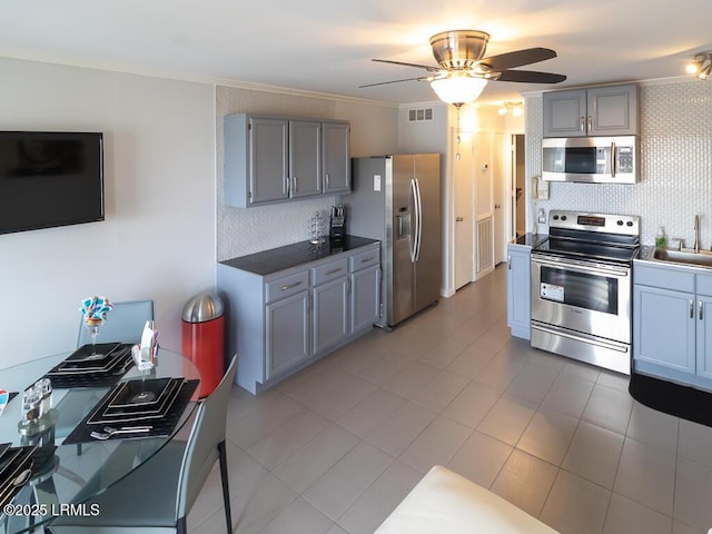 kitchen with sink, ornamental molding, gray cabinets, stainless steel appliances, and decorative backsplash