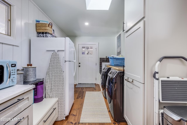 washroom featuring a skylight, light hardwood / wood-style floors, and washing machine and dryer